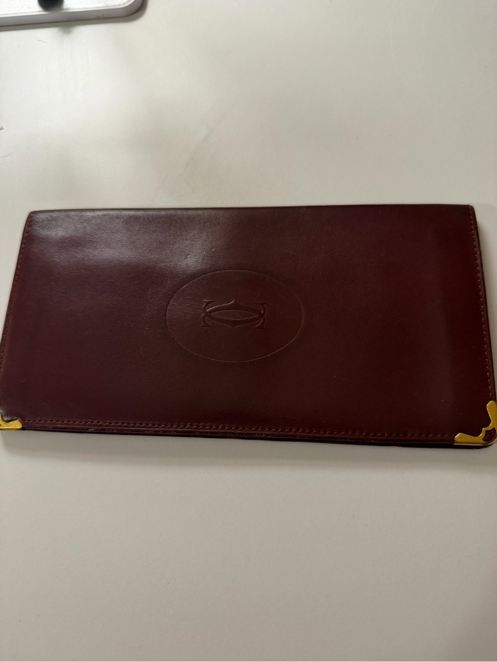 Cartier Burgundy Leather Wallet with Embossed Oval Logo and Gold Corners